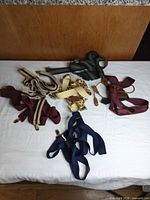 All seven pairs of suspenders spread on white surface showing color variety and hardware