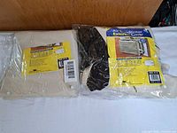 Front view of both packaged beige vinyl A/C covers with AC-Safe labels and straps visible