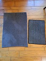 Both bath rugs side by side on wood floor for size comparison