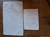 Both bath mats side by side on floor showing size difference