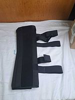 Front view of black TANDCF knee brace showing overall condition and Velcro straps