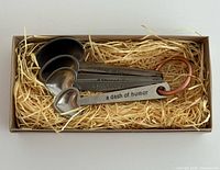 Set of four metal heart measuring spoons in box with straw filler