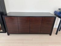 Front view of closed cabinet showing four wood veneer doors, black frame and legs
