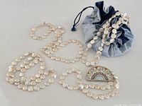Group view of four faux pearl necklaces, mosaic brooch, and fabric pouch