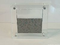 front view of clear acrylic sculpture showing internal spheres and metal panels