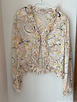 Front view of silk blouse hanging, showing full design and long sleeves