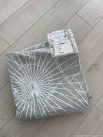 Folded beige/white radial pattern linen fabric with attached product label