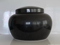 Front view of black-glazed ceramic pot with lid attached
