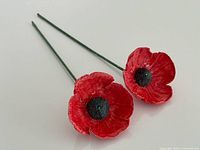 Pair of ceramic poppy stems side by side