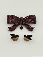 Front view of garnet bow brooch and two fly pins