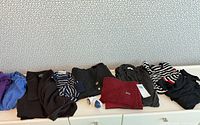 All eight sweaters plus defuzzer laid out on dresser