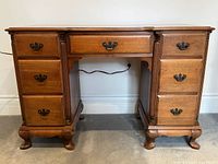 Front view of walnut kneehole writing desk with drawers closed