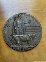 Front view of entire bronze plaque showing Britannia, lion, legend, and name inscription