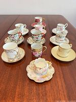 All ten cup and saucer sets plus extra Nippon cup displayed on wooden table
