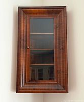 Full view of wall-mounted mahogany cabinet with glass door