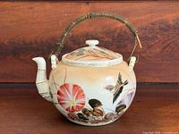 Right side view of teapot showing floral and bird decoration and handle