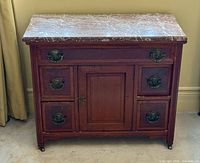 Front view of washstand showing marble top, drawers, cupboard door and casters