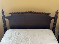 Front view of dark wood twin headboard with spool-turned posts and crest rail