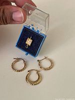 Pendant in box, three hoop earrings displayed on surface