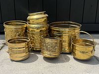 Group shot of six brass planters showing variety of shapes and designs