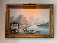 Framed painting with attached picture light displayed on wall