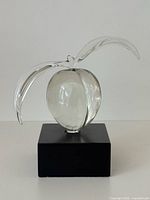 Front view of clear glass peach sculpture on black base