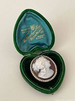 Brooch in open green velvet heart case showing cameo carving and seed pearl border