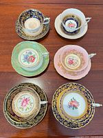 Six assembled teacup and saucer pairs displaying colour and pattern variation