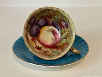 Cup displayed in saucer showing interior fruit artwork