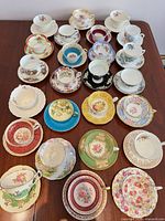 All 25 teacup and saucer sets laid out on table