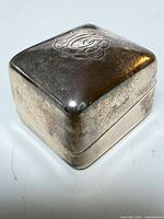 Angled view of closed sterling ring box showing monogram and tarnish