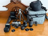 Group view of camera, four lenses, flash, tripod, bags, caps visible