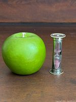 Apple next to sterling silver hourglass egg timer for scale
