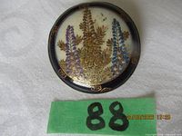 Front view of round Satsuma brooch showing floral design and metal rim