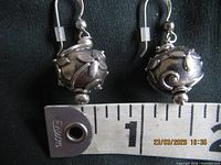 pair of sterling silver floral ball earrings beside ruler