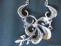 Front view of sterling silver pendant showing scroll and leaf design
