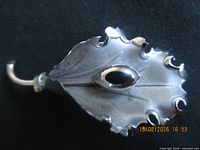 Front view of sterling silver leaf brooch showing scalloped edges and central oval accent