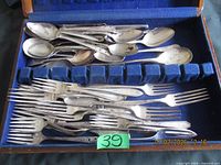 Open wooden flatware chest showing spoons in upper section and forks in lower section