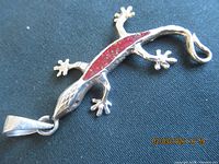 Front view of silver-tone lizard pendant with red inlay