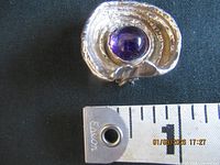 Front view showing concentric silver design and purple cabochon