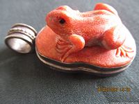 Side view showing orange frog carving and silver bail