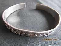 Full view of sterling silver cuff bangle on dark fabric