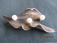 front view of brooch showing three pearls and folded design