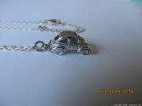 Side view of silver VW Bug pendant attached to chain