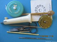 All items laid out on blue background showing daisy wheel, tape measure, punch tool, scissors, snips, darning mushroom and needles