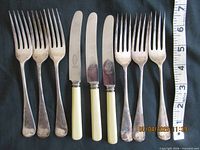 Group of forks and knives with tape measure for scale