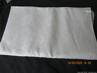 Folded white linen damask tablecloth on surface