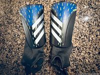 Front view of both shin guards showing shell graphics and ankle sleeves