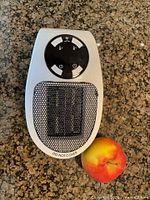 Front view showing mesh grille, control panel, size reference apple not included