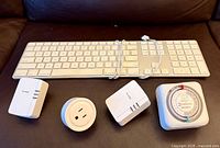 Front view of keyboard, two powerline adapters, smart plug, and mechanical timer